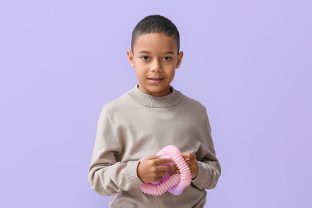 Little African-American boy with pink Pop Tube on lilac backgroundの写真素材
