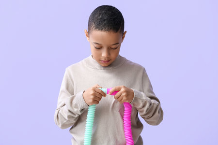 Little African-American boy with Pop Tubes on lilac backgroundの写真素材