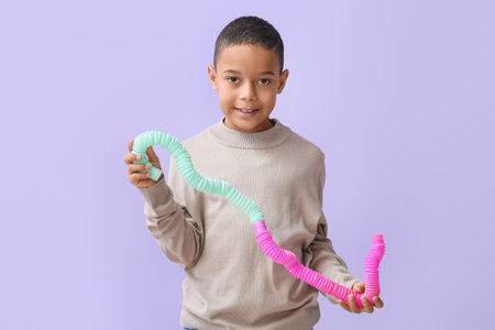 Little African-American boy with Pop Tubes on lilac backgroundの写真素材