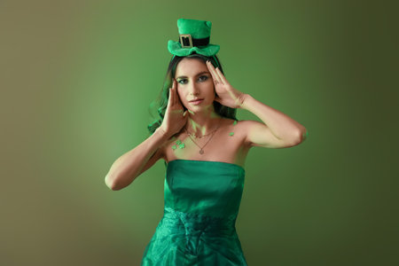 Stylish young woman dressed for St. Patrick's Day party on green backgroundの写真素材