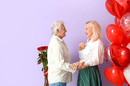 Happy mature man greeting his wife on Valentine's Day against color backgroundの写真素材