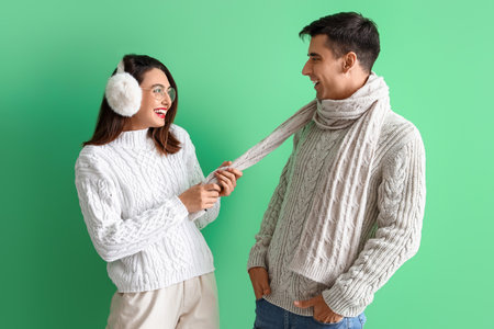 Happy young couple in warm sweaters on color backgroundの写真素材
