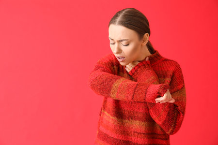 Ill young woman with sore throat on red backgroundの写真素材