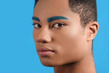 Fashionable young guy with unusual eyebrows on color background
