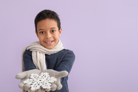 Cute little African-American boy in winter clothes and with snowflake on color backgroundの写真素材
