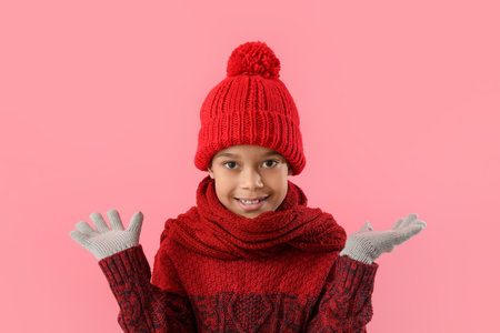 Cute little African-American boy in winter clothes on color backgroundの写真素材