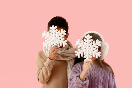 Cute little children in winter sweaters and with snowflakes on color backgroundの写真素材