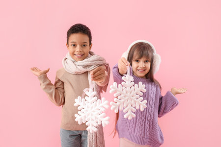 Cute little children in winter sweaters and with snowflakes on color backgroundの写真素材