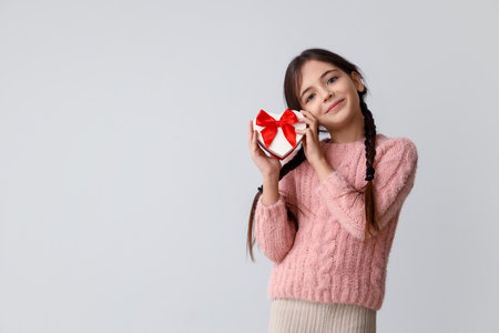 Funny little girl with gift on gray background. Valentine's Day celebrationの写真素材