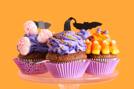 Stand with tasty Halloween cupcakes on orange background, closeupの写真素材