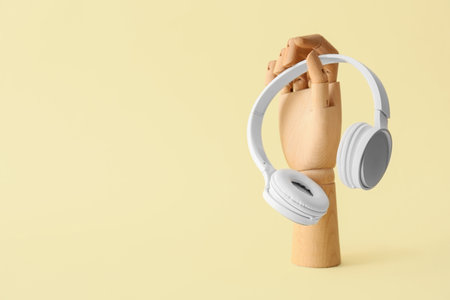 Wooden hand with headphones on yellow backgroundの写真素材