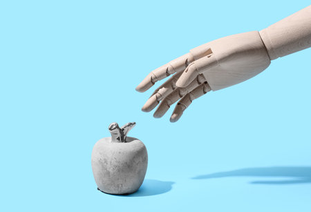 Wooden hand and stone apple on blue backgroundの写真素材