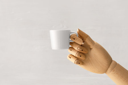 Wooden hand with cup on light background
