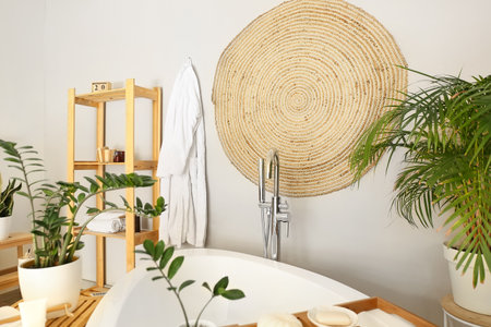 Interior of stylish bathroom with hanging wicker carpet on light wallの写真素材