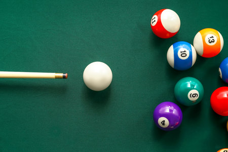 Colorful billiard balls with cue on table