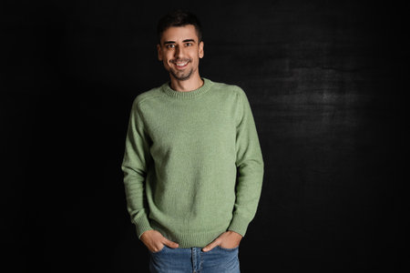 Handsome young man in knitted sweater on dark background