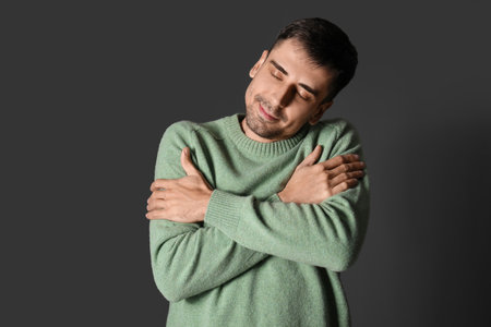 Handsome young man in knitted sweater on dark backgroundの写真素材
