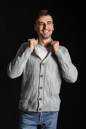 Handsome young man in knitted sweater on dark backgroundの写真素材