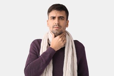 Ill young man with sore throat on white background
