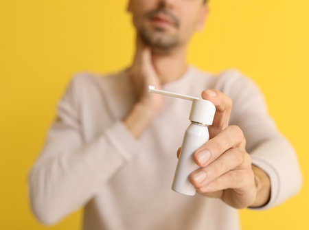Ill young man with inhaler on yellow background, closeupの写真素材
