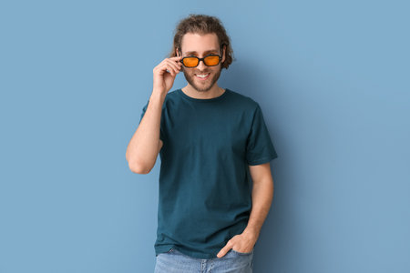 Handsome young man in stylish t-shirt on blue backgroundの写真素材