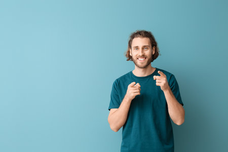 Handsome young man in stylish t-shirt on blue backgroundの写真素材