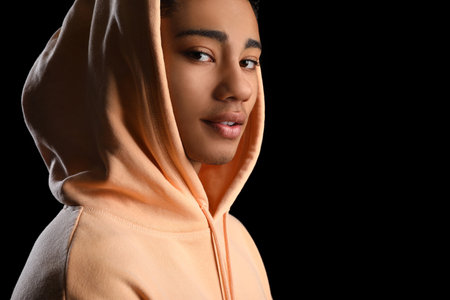 African-American teenage boy in hoodie on black background, closeupの写真素材