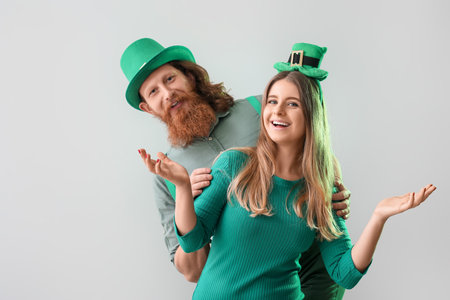 Happy young couple in hats on light background. St. Patrick's Day celebrationの写真素材
