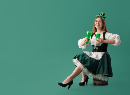 Happy young woman with glasses of beer on green background. St. Patrick's Day celebrationの写真素材