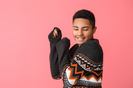 Handsome African-American guy in knitted sweater on color backgroundの写真素材