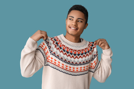 Handsome African-American guy in knitted sweater on color backgroundの写真素材