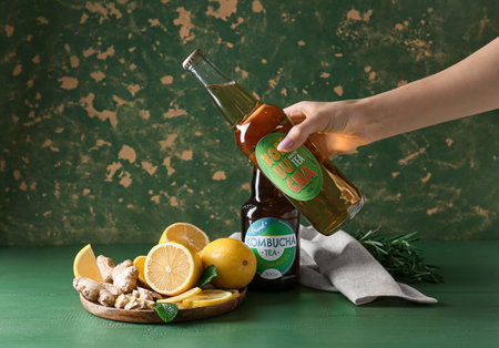 Female hand with natural kombucha and ingredients on table