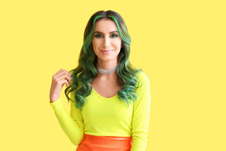 Beautiful young woman with unusual green hair on color background