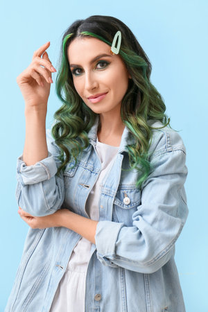 Beautiful young woman with unusual green hair on color backgroundの写真素材