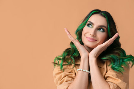 Beautiful young woman with unusual green hair on color backgroundの写真素材