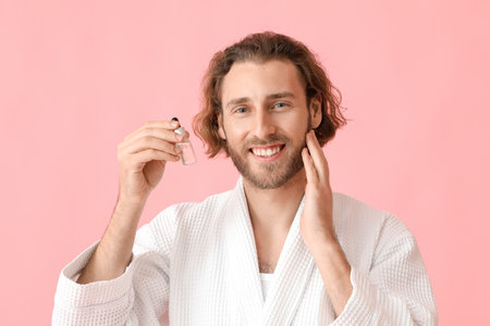 Young man with cosmetic serum on color backgroundの写真素材