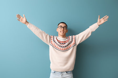 Handsome young Asian man in knitted sweater on blue backgroundの写真素材