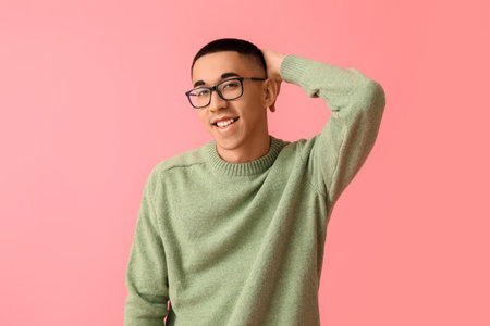 Handsome young Asian man in knitted sweater on pink backgroundの写真素材