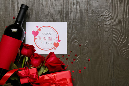 Composition with bottle of wine, roses and card for Valentine's Day on wooden backgroundの写真素材