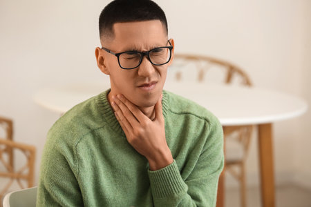 Ill Asian man with sore throat at home