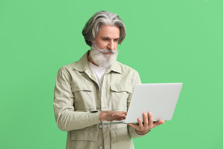 senior man using laptop on green background