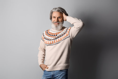 Handsome senior man in knitted sweater on gray backgroundの写真素材