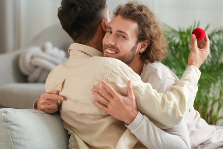 Happy engaged gay couple hugging at homeの写真素材