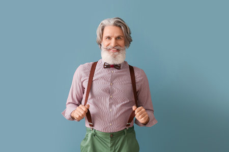 Bearded senior man with suspenders on gray backgroundの写真素材