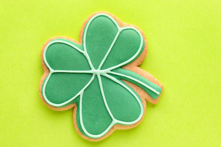 Tasty gingerbread cookie in shape of clover leaf for St. Patrick's Day celebration on green...