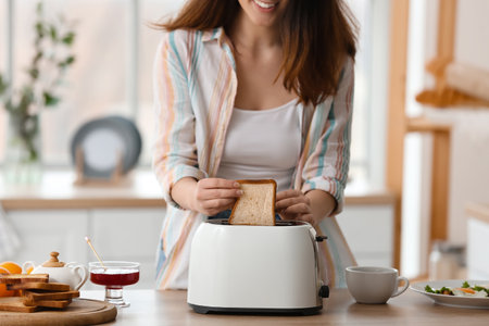 Beautiful young Asian woman making tasty toasts in the kitchenの写真素材