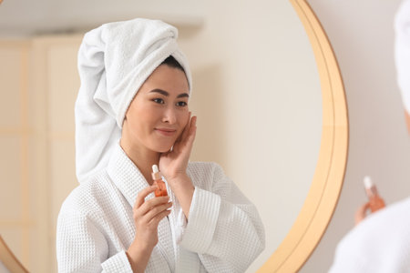 Young Asian woman using cosmetic serum in bathroomの写真素材