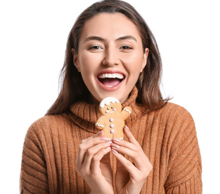 Happy young woman with tasty gingerbread cookie on white background