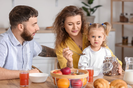 Happy young family having breakfast in the kitchen at homeの写真素材