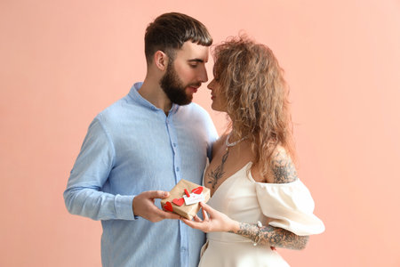 Happy couple with gift for Valentine's Day on color background